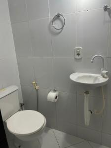 a white bathroom with a toilet and a sink at Casa da Sol in Arraial do Cabo