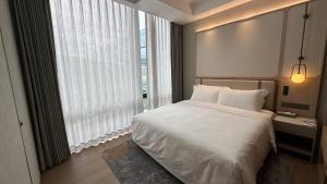 una camera da letto con un letto bianco e una grande finestra di Also Hotel a Shanghai
