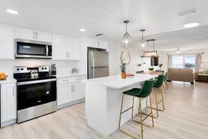 a kitchen with white cabinets and a kitchen island with green chairs at Cocoa Beach Towers 52 in Cocoa Beach +220 photos
