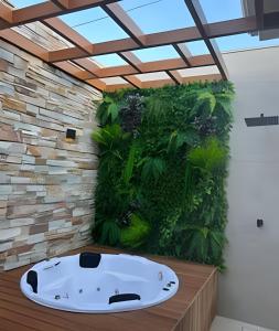 Eine Badewanne in einem Zimmer mit einer Pflanzenwand. in der Unterkunft Casa Bela - Centro in Águas de Lindóia