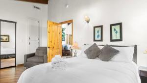 a bedroom with a large white bed and a chair at The Fairway Hideaway by AvantStay Game Room Outdoor Dining Near Lake Arrowhead in Lake Arrowhead +42 photos