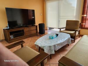 a living room with a flat screen tv and a coffee table at Ben's House Bangsaen in Bangsaen