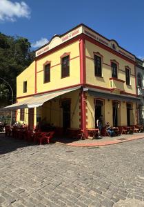 un bâtiment jaune et rouge avec des tables et des chaises dans l'établissement Pousada Elite, à Santa Teresa