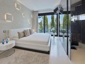 a bedroom with a white bed and a large window at Villa in Ibiza with Infinity Pool and Sea Views in Es Cubells +30 photos
