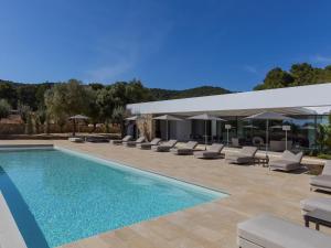 Una piscina con tumbonas y un edificio. en Villa in Ibiza with Mountain Views & Pool, en Santa Eulària des Riu