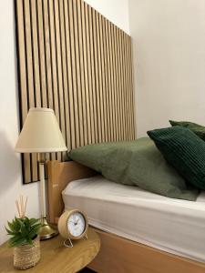 a bed with green pillows and a clock on a table at Zentrale Gästezimmer am Marienplatz - London in Stuttgart