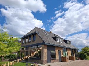 a house with a black roof and a sky at Group accommodation for 36 guests in Scherpenzeel
