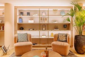 two chairs and a table in a room with shelves at NYX Hotel Amsterdam Rembrandt Square in Amsterdam