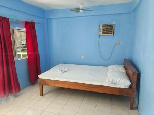 a blue room with a bed with a fan and a window at Satosa Beach Resort in San Joaquin +4 photos