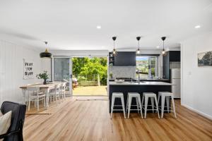 a kitchen and living room with a table and chairs at Bluegum Beach Stay in Narrawallee