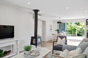 a living room with a fireplace and a tv at Bluegum Beach Stay in Narrawallee