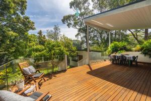 a wooden deck with chairs and tables on it at Bluegum Beach Stay in Narrawallee