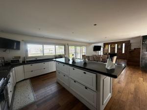 a large kitchen with white cabinets and a black counter top at Casa quinta a minutos de La Plata in Berisso