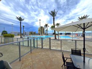 a pool with palm trees and a table with an umbrella at Lux Vista Retreat, 2BR, 2BA with terrace and pool in Fort Myers