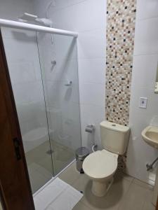 a bathroom with a toilet and a glass shower at Pousada Alvorada in Engenheiro Coelho