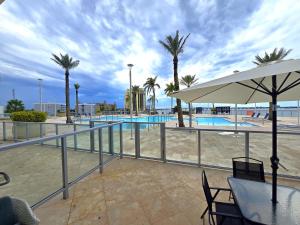 a pool with palm trees and a table with an umbrella at Lux Vista Retreat, 2BR, 2BA with terrace and pool in Fort Myers