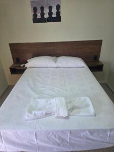 un letto bianco con un paio di asciugamani sopra di Pousada Alvorada a Engenheiro Coelho