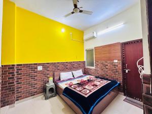 Cama en habitación con pared amarilla en shri radha ji guest House, en Vrindāvan