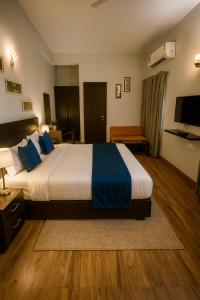 a hotel room with a large bed with blue pillows at Pearl Grand Boutique Cottage In Omaxe Anandam Vrindavan -# Premium AC Rooms With Balcony # Big Parking # Lift # Garden # Peaceful Area # Near Prem Mandir # Property Of The Year # Most Awarded in Vrindāvan