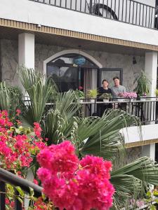 two people sitting at a table on a balcony with flowers at Villa Full House in Vũ Lâm