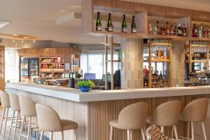 Campanile Reims Centre - Cathedrale في رانس: بار به المقاعد وزجاجات من النبيذ