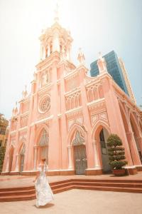a woman in a wedding dress walking in front of a church at ORANGE Hotel - near Dragon Bridge, In the Heart of the City, Warm as Home in Da Nang