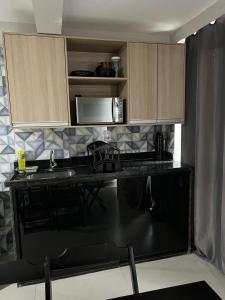 a kitchen with a black counter top and wooden cabinets at Catamarã Pé na Areia in Angra dos Reis