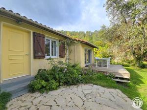 una casa con una puerta amarilla y un porche de madera en Gîte rural à Saint-Cybranet avec piscine privée, animaux admis - FR-1-616-502, en Saint-Cybranet