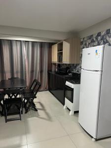 a kitchen with a white refrigerator and a table at Catamarã Pé na Areia in Angra dos Reis