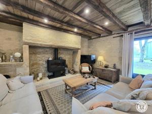 a living room with couches and a fireplace at Maison en pierres au cœur du Périgord, 10 personnes, charme authentique - FR-1-616-508 in LʼAir