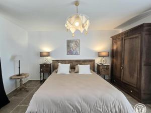 a bedroom with a large bed and a chandelier at Maison en pierres au cœur du Périgord, 10 personnes, charme authentique - FR-1-616-508 in LʼAir