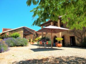 una mesa y sillas con sombrilla frente a una casa en Charmante maison Périgord avec piscine privée et WIFI - FR-1-616-511, en Fonvielle