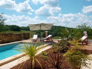 Un patio con sillas y sombrilla y una piscina. en Charmante maison Périgord avec piscine privée et WIFI - FR-1-616-511, en Fonvielle