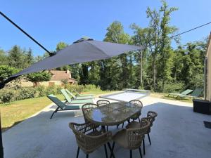 a patio with a table and chairs and an umbrella at Charmante maison avec piscine chauffée privée au cœur du Périgord Noir - FR-1-616-530 in Prats-de-Carlux