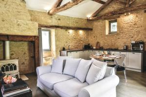 ein Wohnzimmer mit einer weißen Couch und einer Küche in der Unterkunft Charming Mas With Medieval Church Views in Sainte-Croix-de-Beaumont
