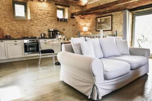 ein Wohnzimmer mit einer weißen Couch und einer Küche in der Unterkunft Charming Mas With Medieval Church Views in Sainte-Croix-de-Beaumont