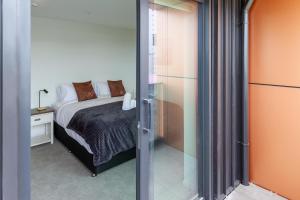 Un dormitorio con una cama y una puerta de cristal. en Manchester Square Urban Stay - Easy To Everything, en Christchurch