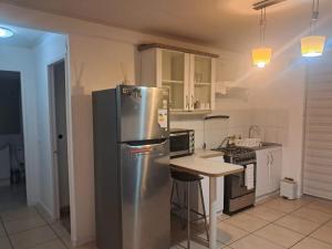 a kitchen with a stainless steel refrigerator and a table at Sector Norte 1 Dormitorio in Antofagasta