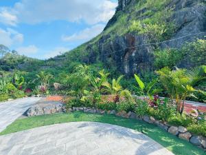 ein Garten mit einem Steinweg vor einem Berg in der Unterkunft Trang An River Sunshine Bungalow in Xuân Sơn