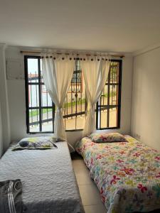 Finca Fusagasugá Villa Luisa في فوساغاسوغا: سريرين في غرفة ذات نافذتين