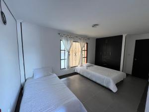 Finca Fusagasugá Villa Luisa في فوساغاسوغا: غرفة نوم بها سريرين ونافذة