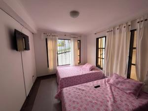 Finca Fusagasugá Villa Luisa في فوساغاسوغا: غرفة بسريرين وتلفزيون ونوافذ