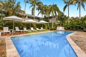 a pool at a resort with chairs and umbrellas at Byron Getaway @the Crest in Byron Bay