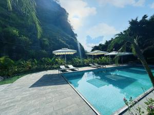 ein Swimmingpool mit Stühlen und Sonnenschirmen neben einem Berg in der Unterkunft Trang An River Sunshine Bungalow in Xuân Sơn