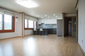 een lege kamer met een keuken en een hardhouten vloer bij welcalm village in Naemulch'i-ri
