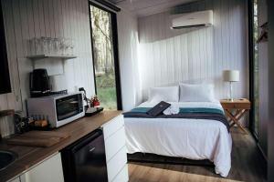 um quarto com uma cama, um micro-ondas e uma televisão em Solitary Islands Farm 2 by Tiny Away em Arrawarra