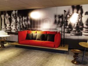 a red couch sitting in a room with a wall with a chess at ibis Hotel Brussels Airport in Diegem