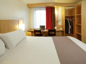 a bedroom with a bed and a desk with a laptop at ibis Hotel Brussels Airport in Diegem +84 photos