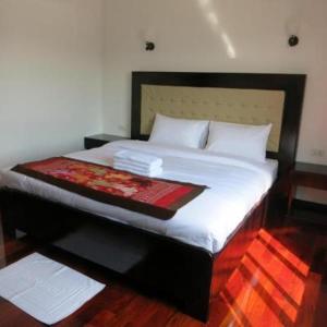 Favanhmai Hotel في Ban Pho Touane: غرفة نوم بسرير كبير مع ملاءات ووسائد بيضاء