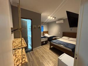 a small room with two beds and a tv at Moreno Guest House com Piscina, churrasqueira Praia de Itaguaré e Riviera in Bertioga +50 photos